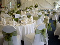 wedding reception with white chairs and green ribbon